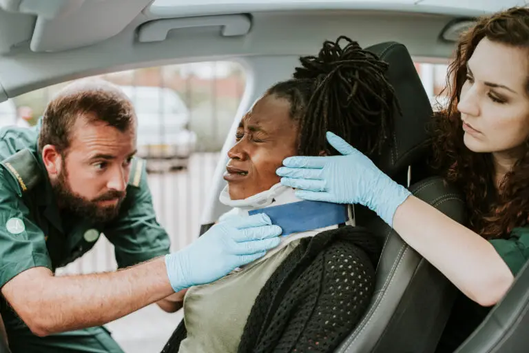 Paramedics helping an injured driver in a car after an accident