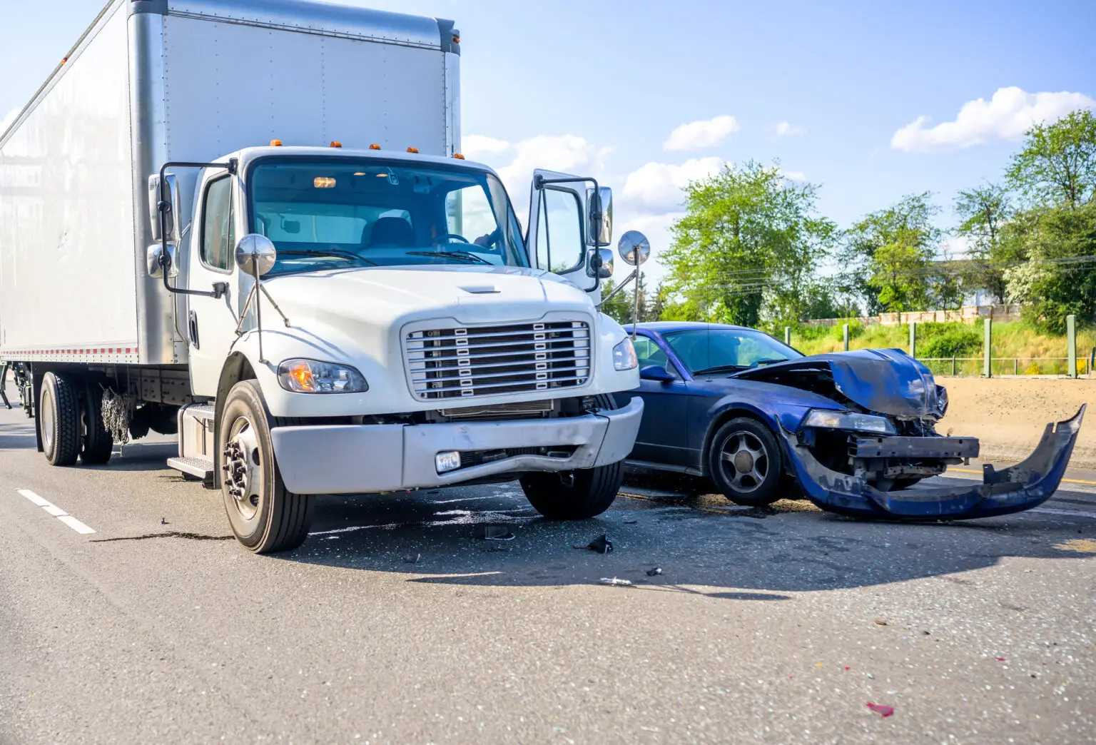 A box truck and a damaged car on the road after a crash